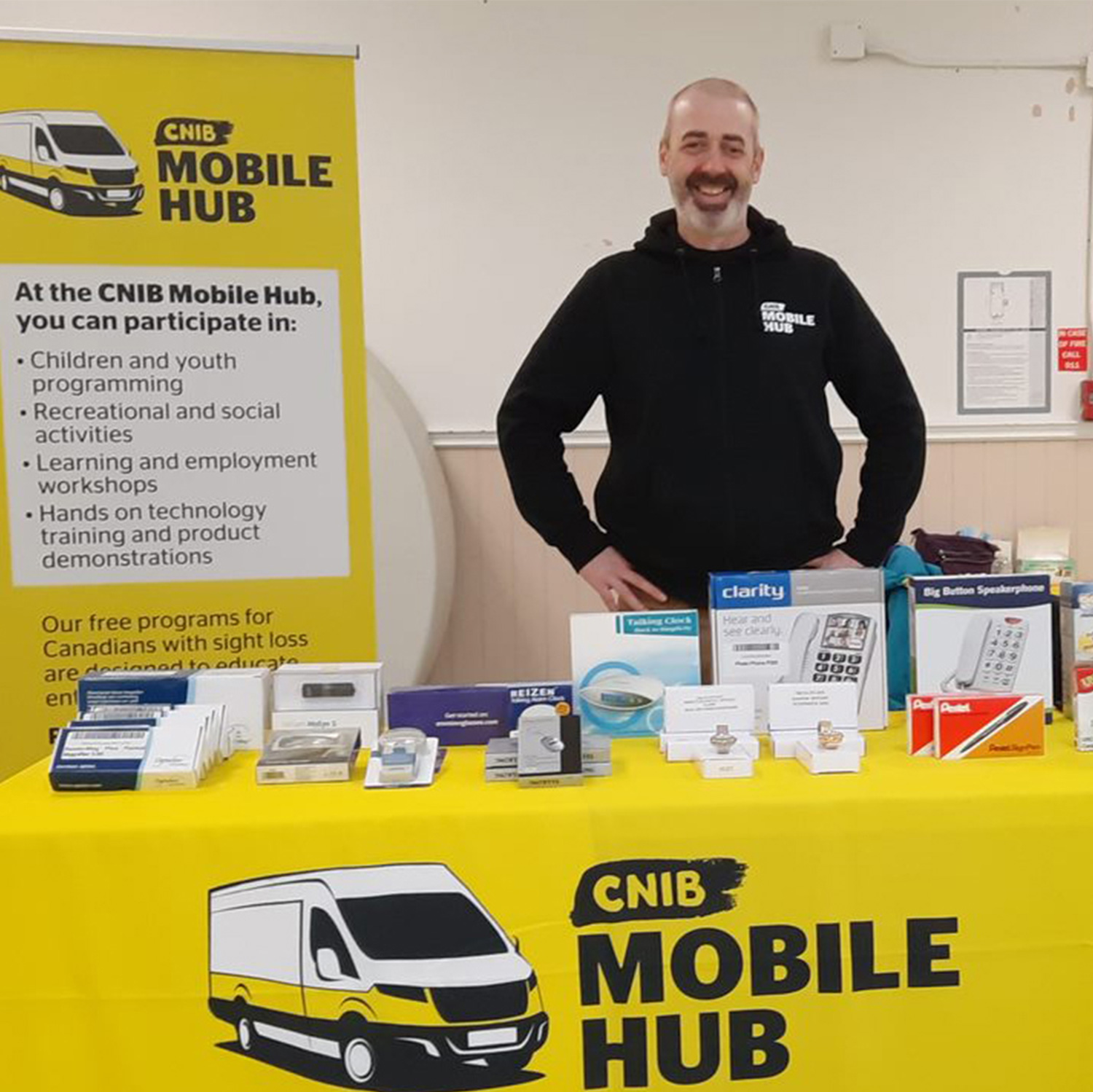 Man standing by CNIB Mobile Hub stand