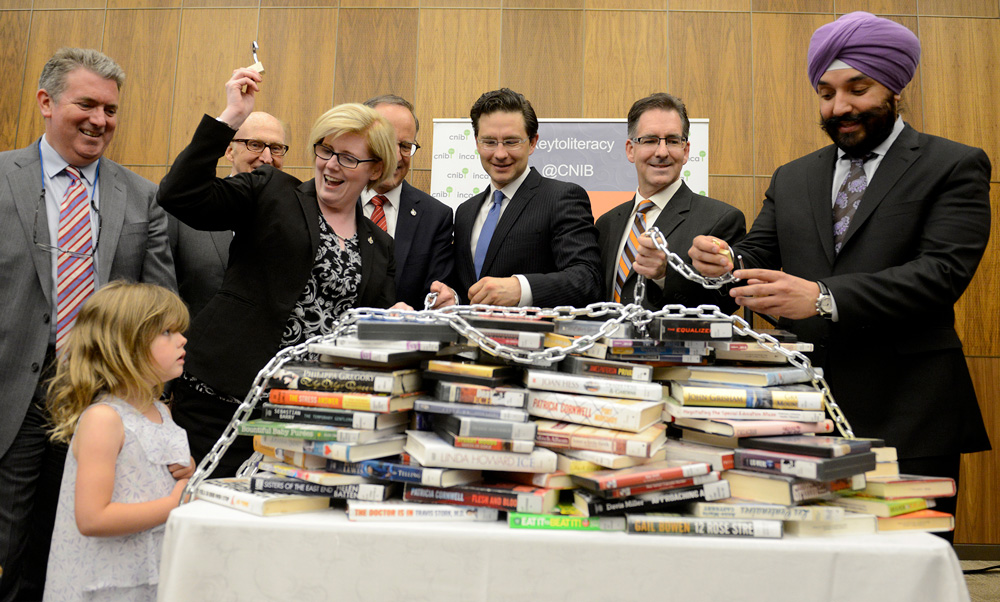 Personnes célébrant autour d’une pile de livres enchaînée sur une table. 