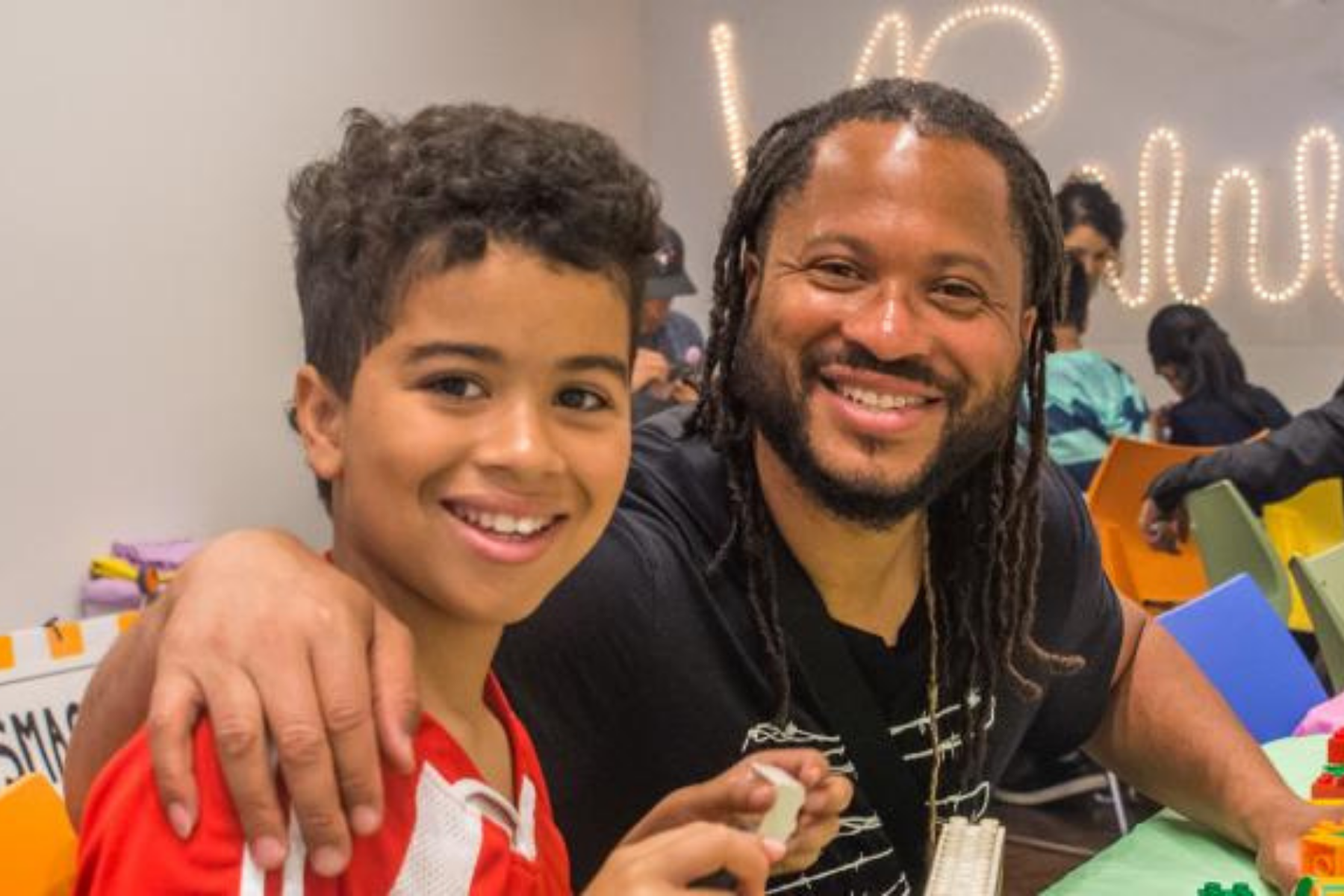 Un père et son fils sourient en construisant des blocs LEGO.