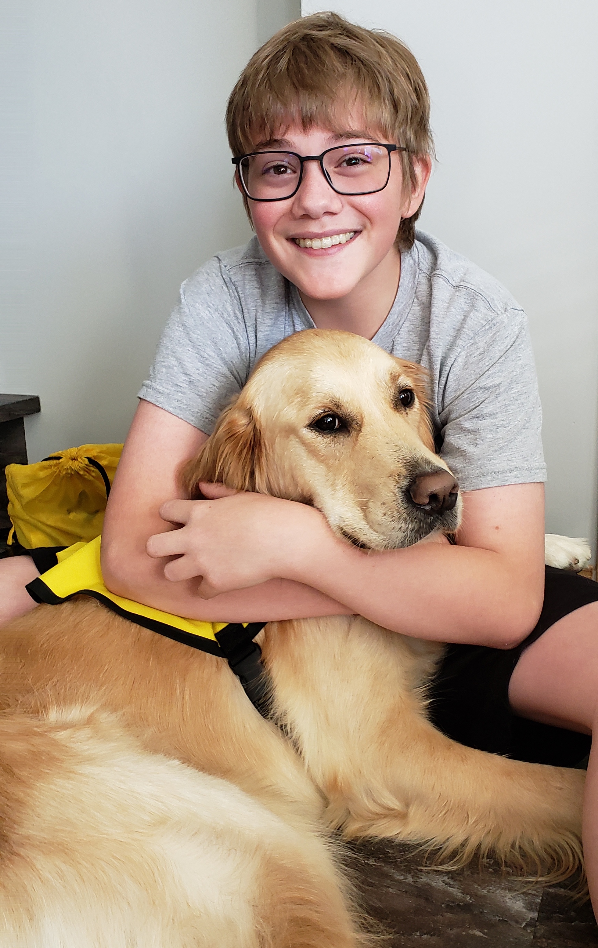 Gabriel assis sur le parquet en bois dur tient dans ses bras la tête de son Golden Retriever. 