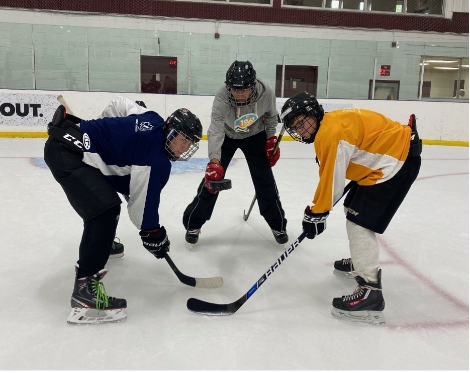 Une mise au jeu. Les joueurs de hockey Brayden, Mathew et Eli s'entraînent sur la patinoire.