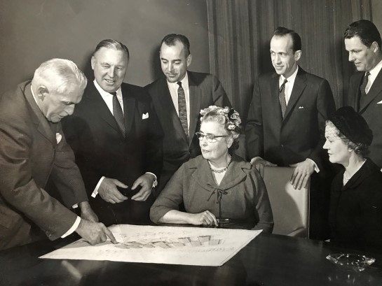 Ancienne photo en noir et blanc du comité de planification de la construction du Centre Lake Joseph passant en revue les plans de conception du Adjustment Training and Holiday Centre (Personnes assises : Elsinore Burns et Margot Brechenridge. Debout, de gauche à droite : Wilfred James (président), Norman Long, J.A Peguegnat, J. Mossop, J.A. Clark).