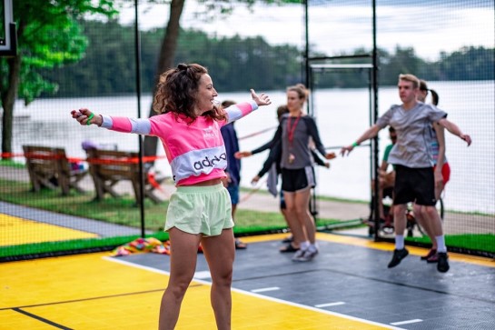 Des participants à un cours de conditionnement physique en plein air sautent sur le terrain multisports.