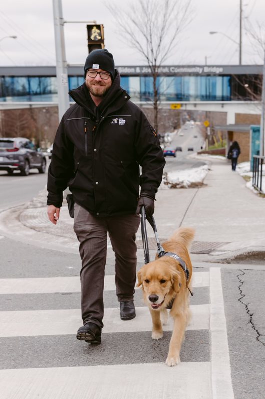Rob Cramer traversant une rue avec un chien-guide en formation