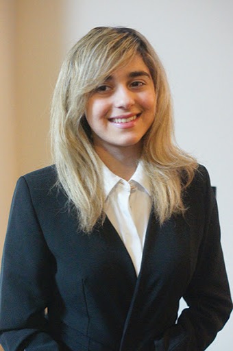 Avesta pose pour une photo d'identité professionnelle. Elle porte un blazer noir et un chemisier blanc. 