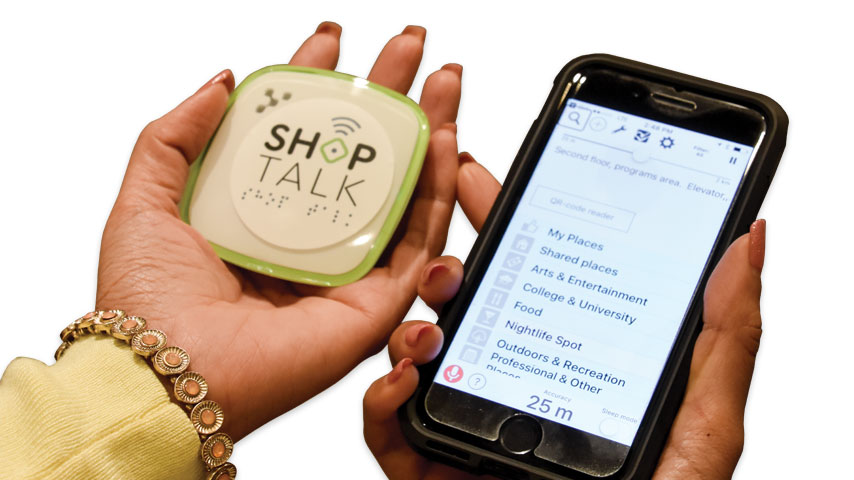 Une femme affichant une balise et un iphone. La main droite tient une petite balise blanche. La main gauche tient un iPhone.