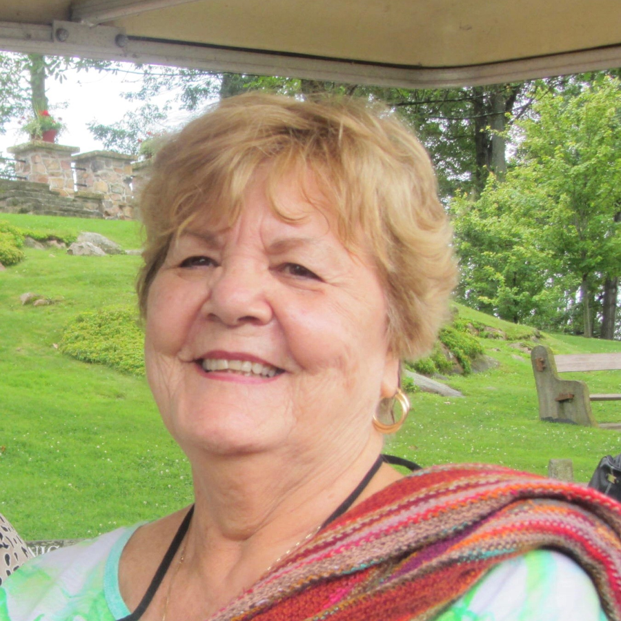 A personal headshot of Claire. She smiles at the camera and sits outdoors.&nbsp;