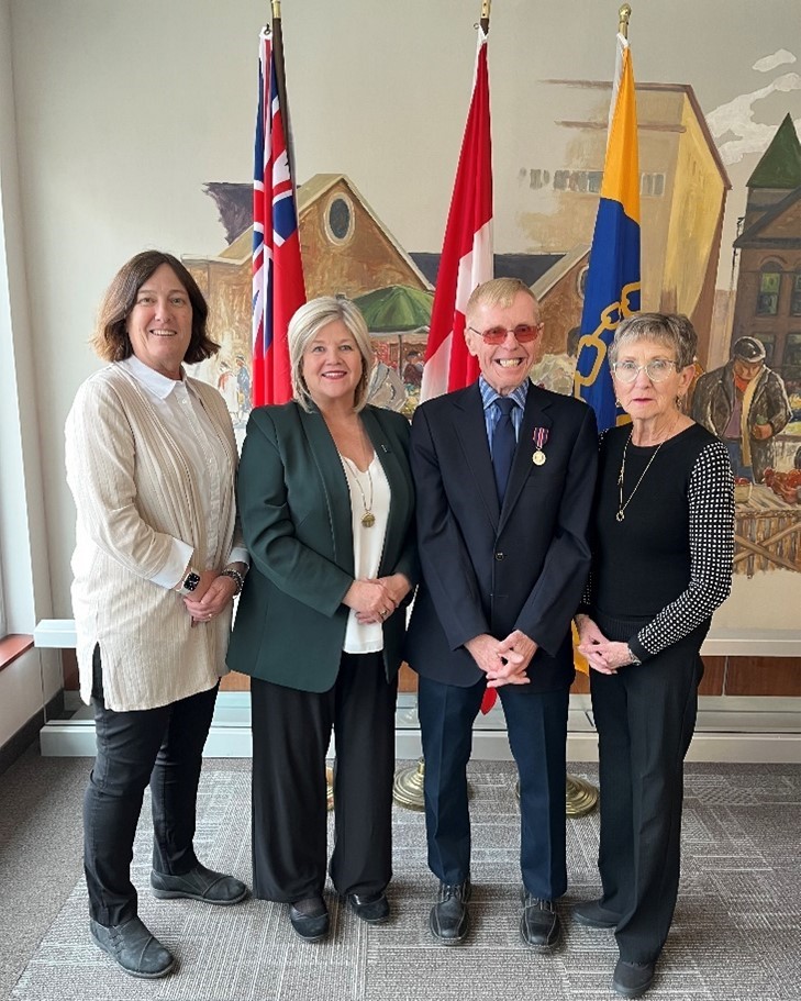 Stephanie Wilsack, le maire Andrea Horvath, Jim Tokos et Heather Tokos (vérifiez le nom de famille) devant trois drapeaux.