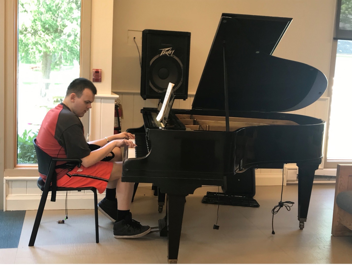 Daniel Kisielewski, invité de la Semaine des adultes 2022 au camp Lake Joe d'INCA, jouant du piano à queue noir dans le salon du centre. 