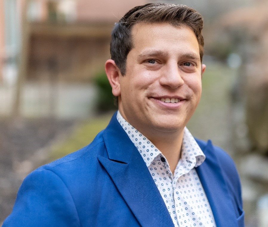 Jacob Charendoff smiles for a professional headshot. He is wearing a stylish blue suit.