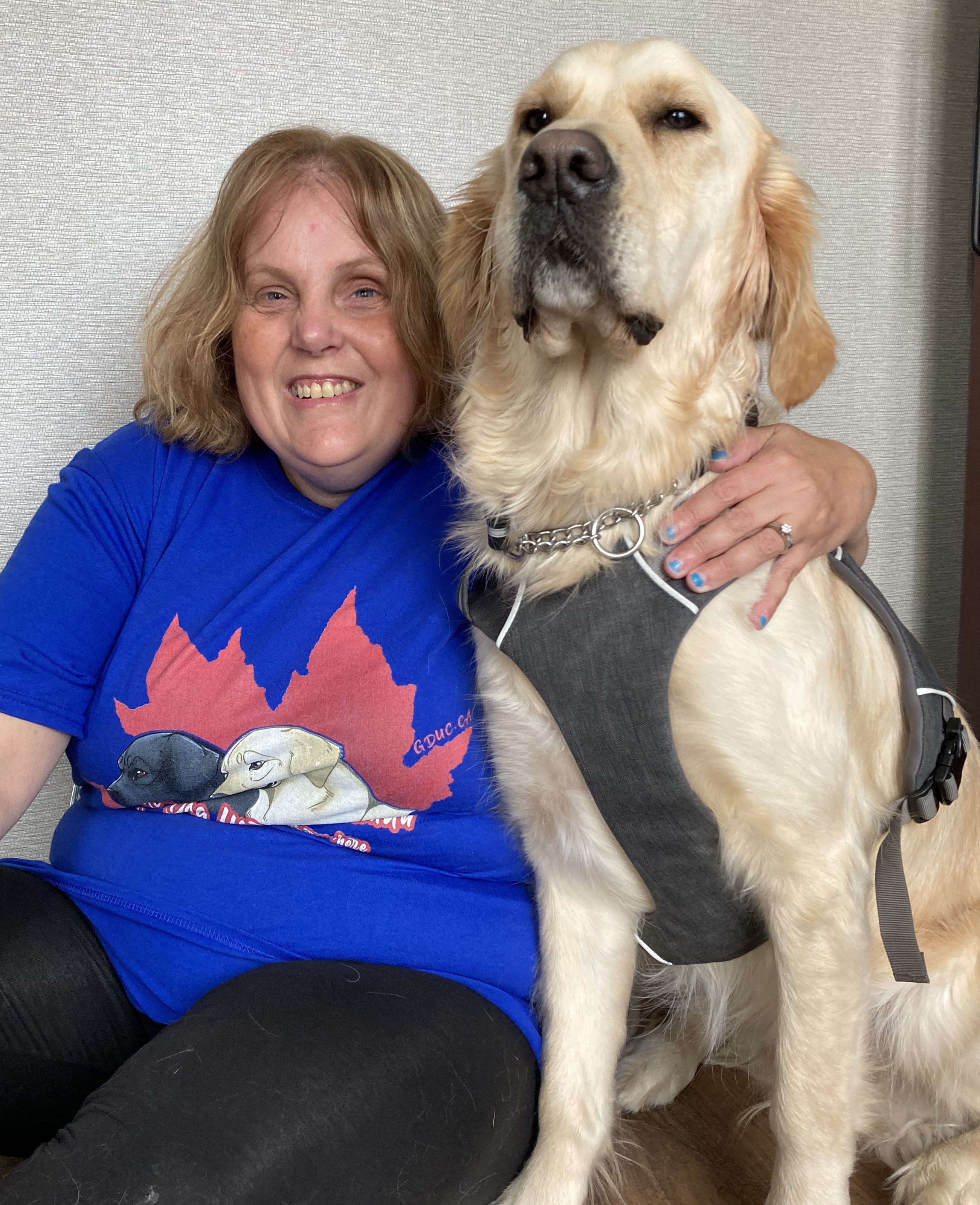 Chris, wearing a blue shirt with a red maple leaf on the front of it, sitting on the floor next to Cody while smiling for the camera.