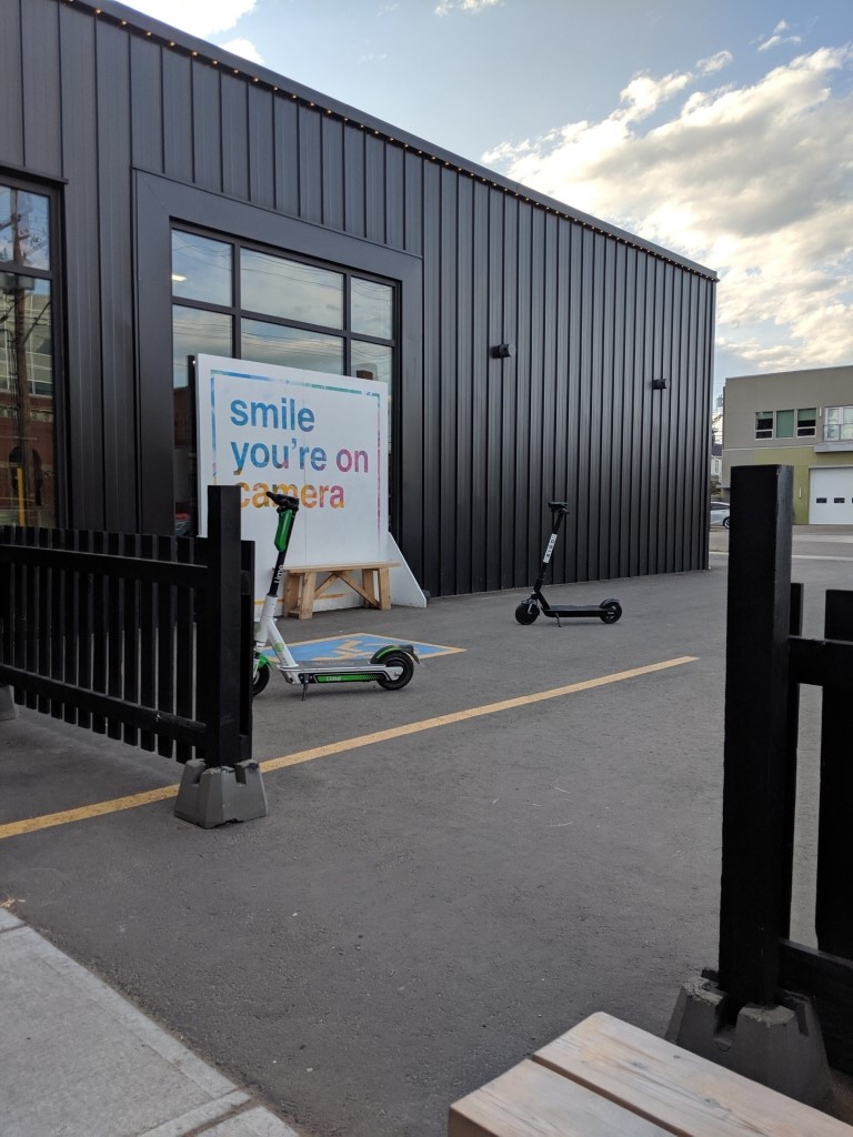 Deux trottinettes électriques disposées côte à côte sur un trottoir à l'extérieur d'un commerce à Edmonton.