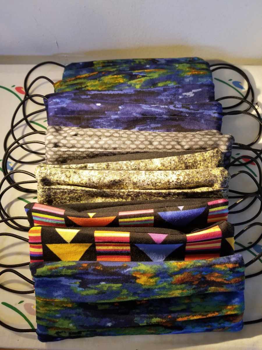 Une pile de masques en tissu artisanaux aux couleurs vives.