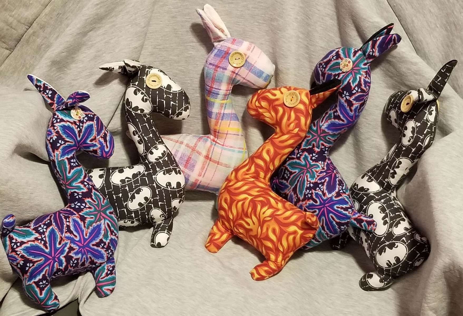Six Llamas en peluche colorés. Les lamas ont des éléments tactiles, comme des yeux en forme de boutons.