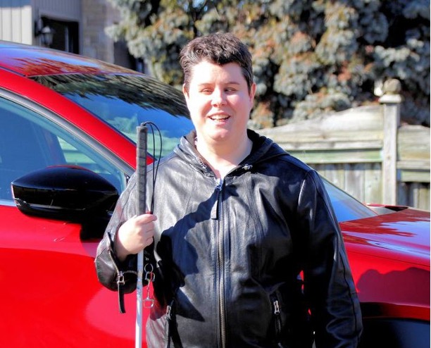 Jade Stolar standing outside holding a white cane.