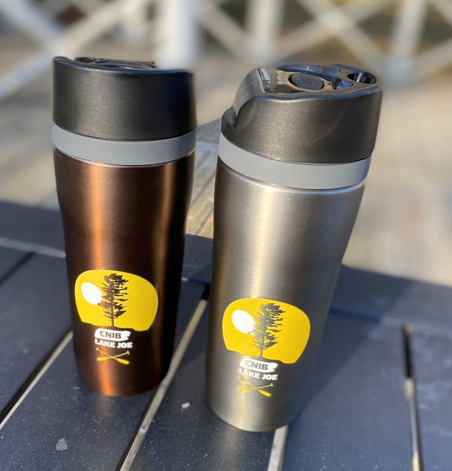 Tasses de voyage en acier inoxydable de couleur bronze et charbon de bois, avec couvercle noir sur une table au camp. 