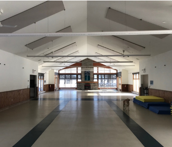 The Dining Hall & Lounge at CNIB Lake Joe. The room is empty of any furniture. Willow, Ambassador Dog, stands to the right-hand side of the room.  