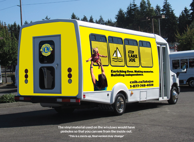 A white minibus is in a parking lot. It is covered in a yellow wrap with “CNIB Lake Joe: Enriching lives. Making memories. Building independence. Cnib.ca/lakejoe 1-877-748-4028” on the side. On the back window is a Lions Club International logo.
