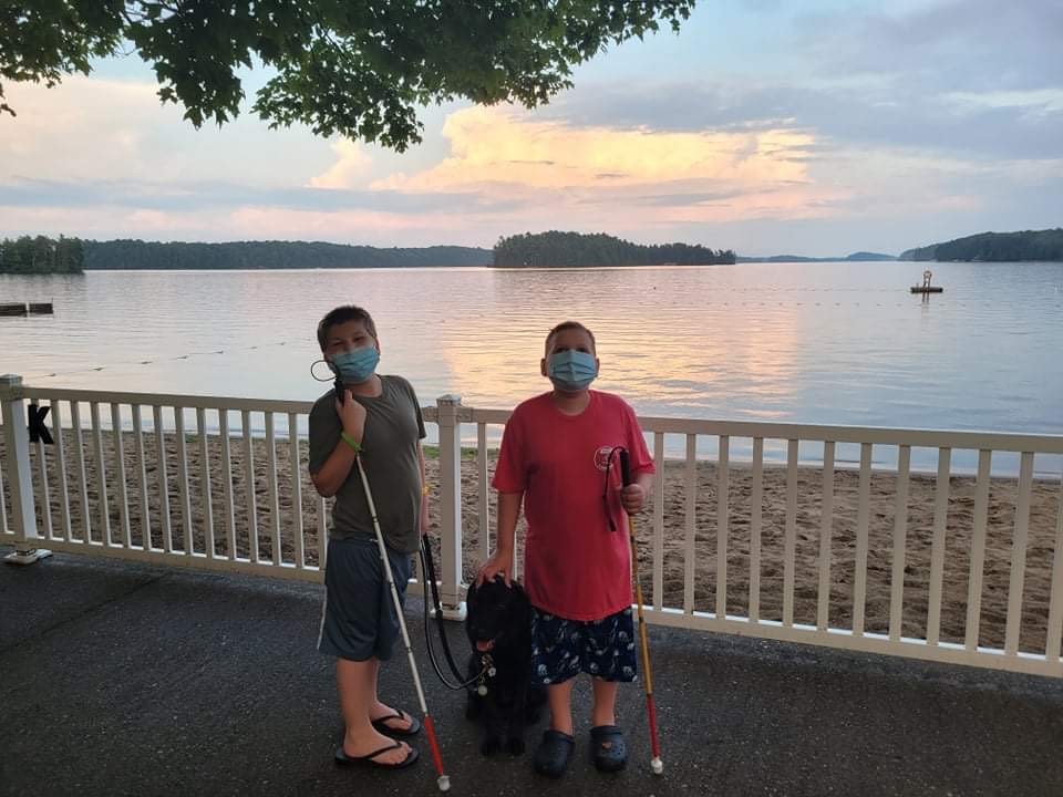 Mason (left) and Ollie (right) and Buddy Dog Hope pose for a picture at Lake Joe. They are wearing face masks and holding their white canes.