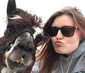 Melyssa pose avec des lunettes de soleil et pince les lèvres avec son amie Lil Chiv, un alpaga. 