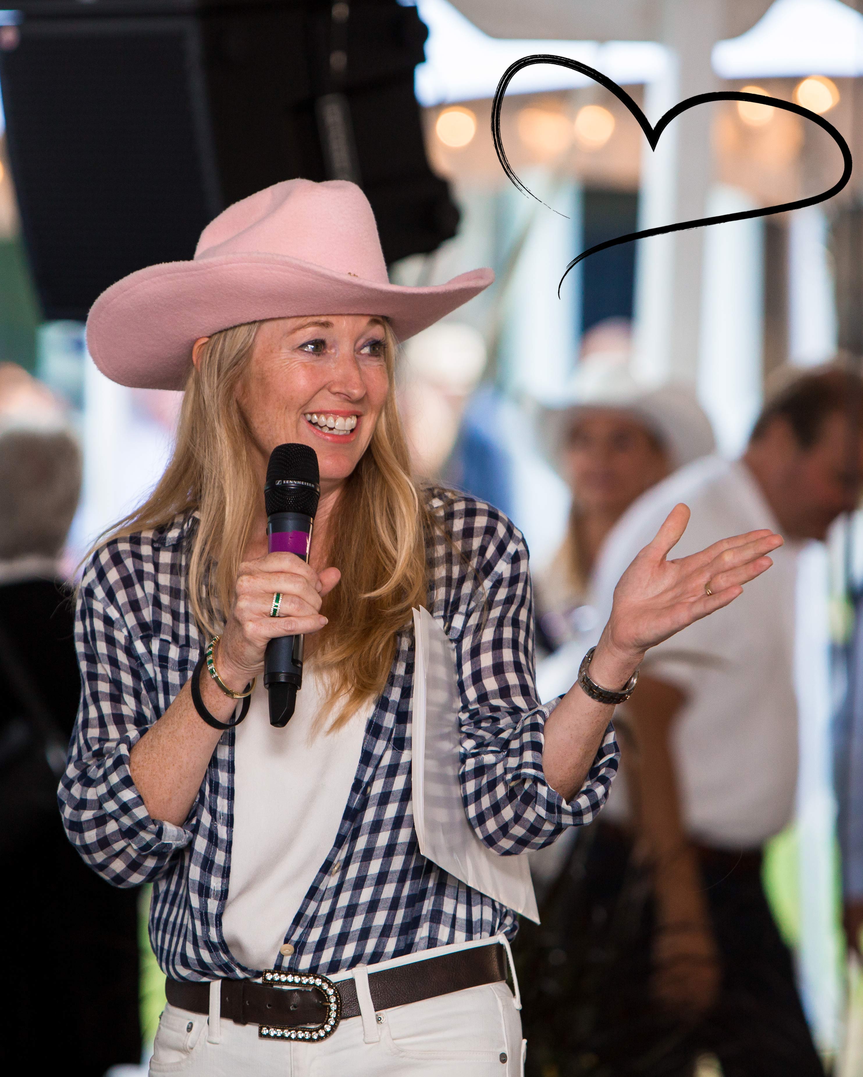 Nancy Simonot wearing a pink cowboy hat and speaking into a microphone at a Lake Joe fundraising event.