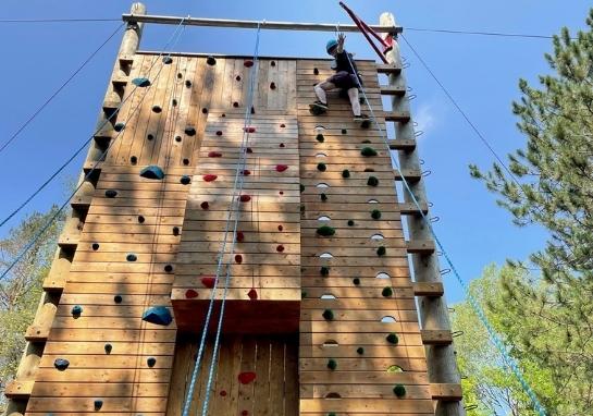 An adult guest at the top of the 32' Climbing Tower, looking down