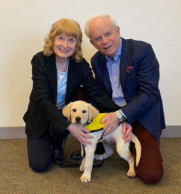 Mary and John Crocker kneel beside a future guide dog.