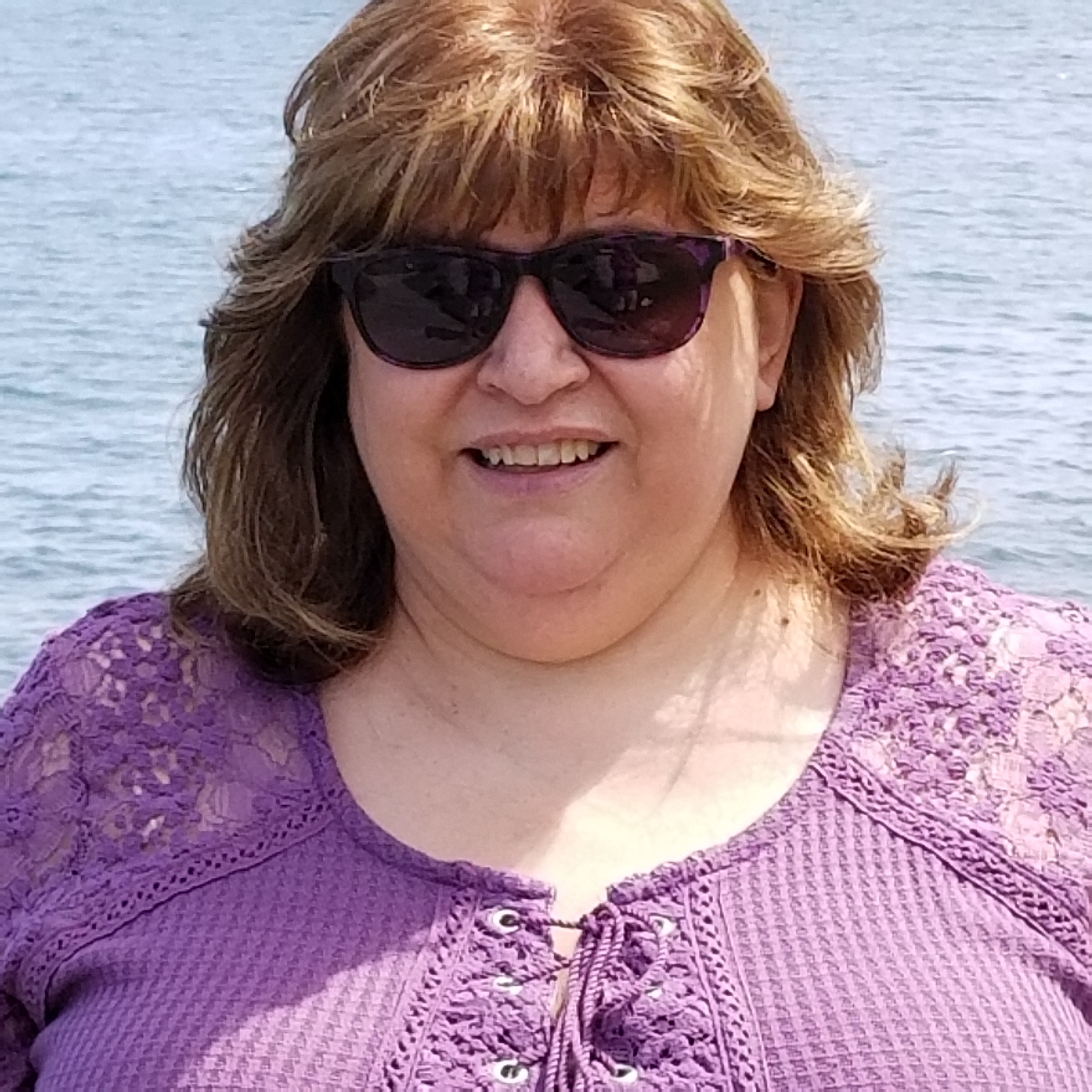 Headshot photo of Marisa, Chair of We are Passengers. A woman with short brown hair wearing sunglasses and a purple top.