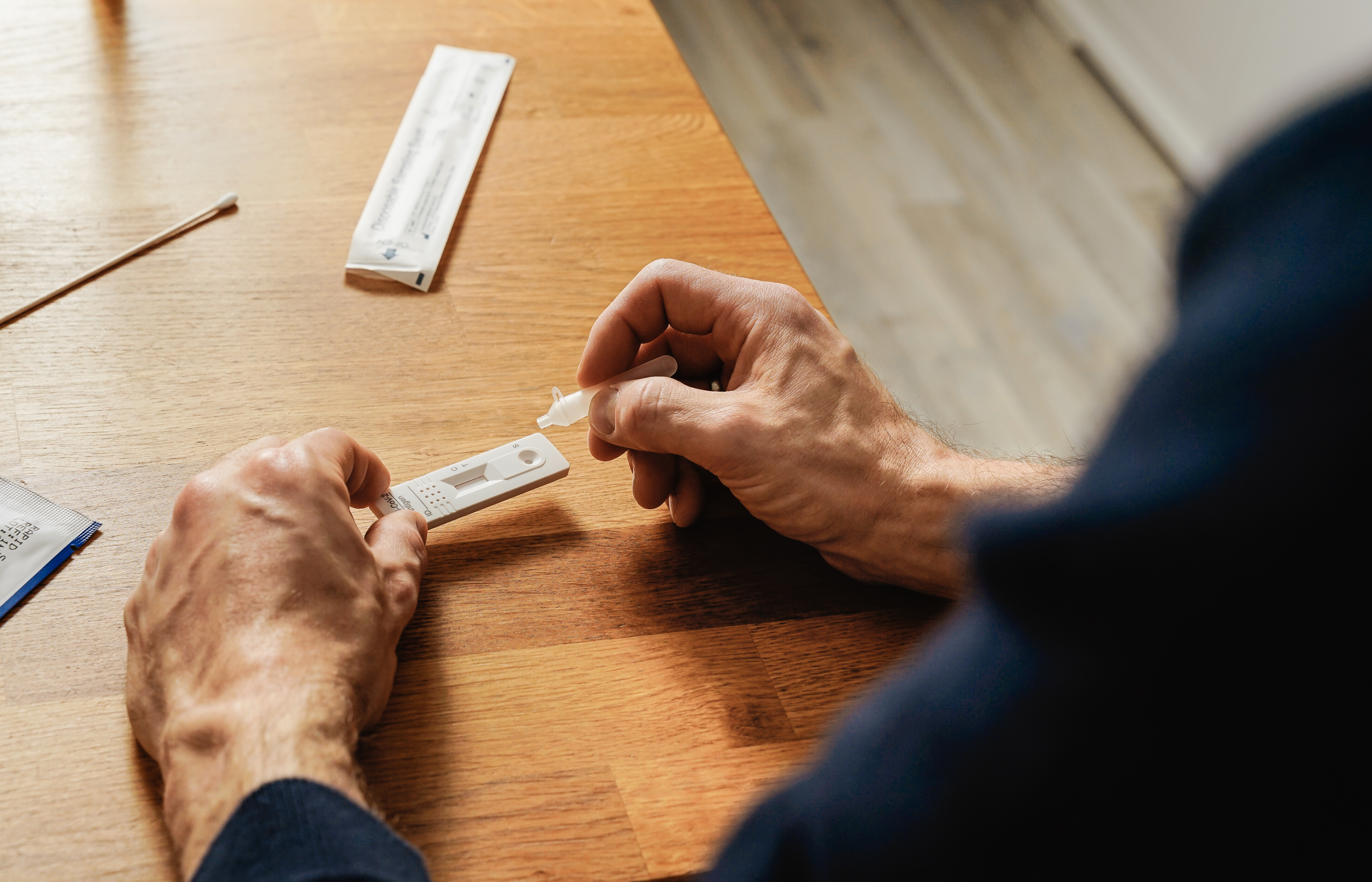 An elderly person using a COVID-19 at home rapid antigen test.