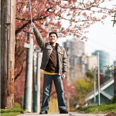 A young man raising proudly his white cane in the air.