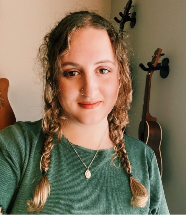 Taylor Gaudot portant ses cheveux en tresses et un haut vert souriant pour une photo.