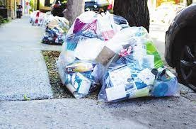 Bacs de poubelles et sac de recyclages à l'extérieur de la voie piétonne.