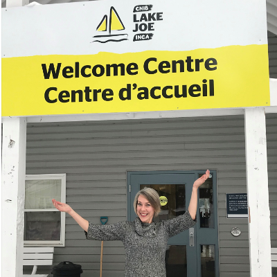 Sherri Helsdingen se tient devant l'enseigne du centre d'accueil du Camp Lake Joe d'INCA.