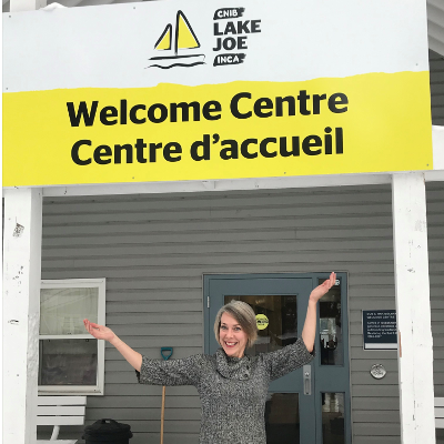 Sherri Helsdingen stands in front of the CNIB Lake Joe Welcome Centre sign. 