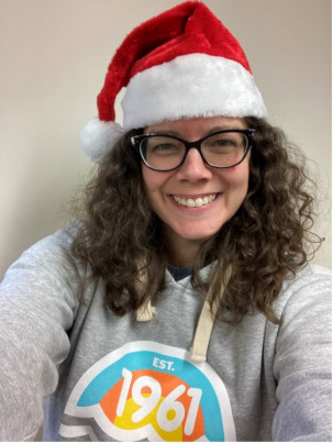 Kelly smiling and wearing her CNIB Lake Joe hoodie and a red Santa hat.