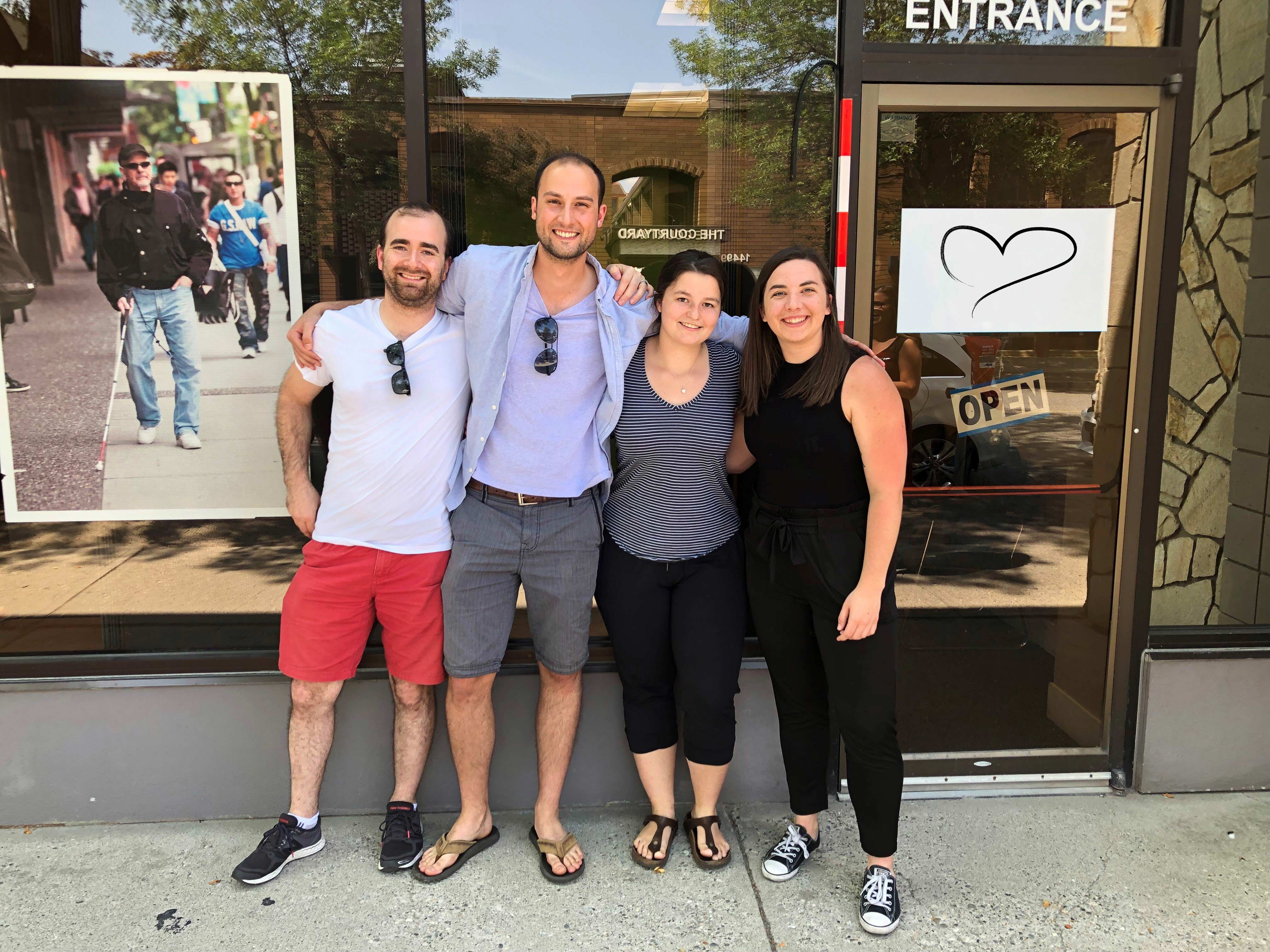 From left to right – Russell Enns, Brian Malcolm, Noemi Stroda and Sierra Sanger, smiling for the camera in front of a CNIB office