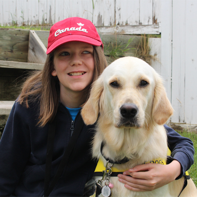 Un jeune garçon qui tient son Golden Retriever avec son bras.