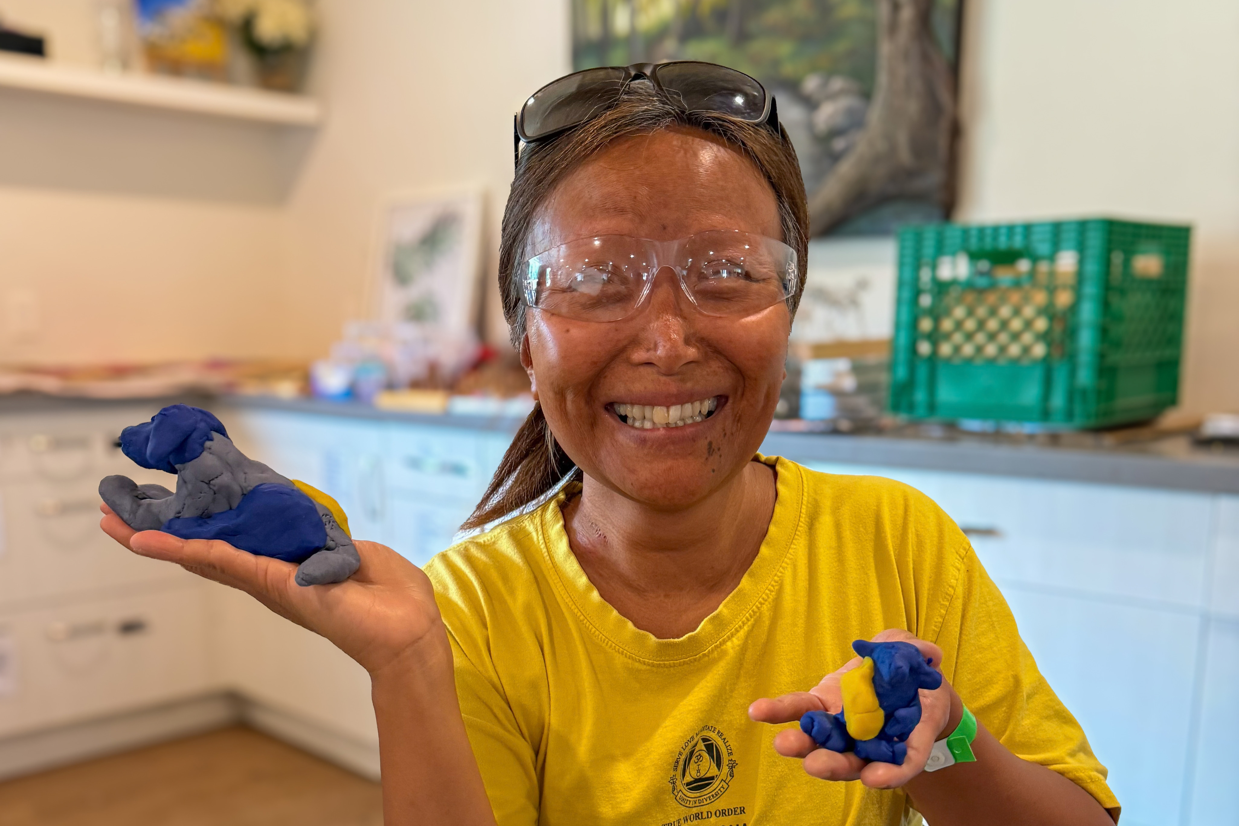 Vivian, une participante à la Semaine intensive d’arts pour jeunes adultes du Camp Lake Joe d’INCA, sourit en brandissant deux petites statues en argile qu’elle a réalisées.