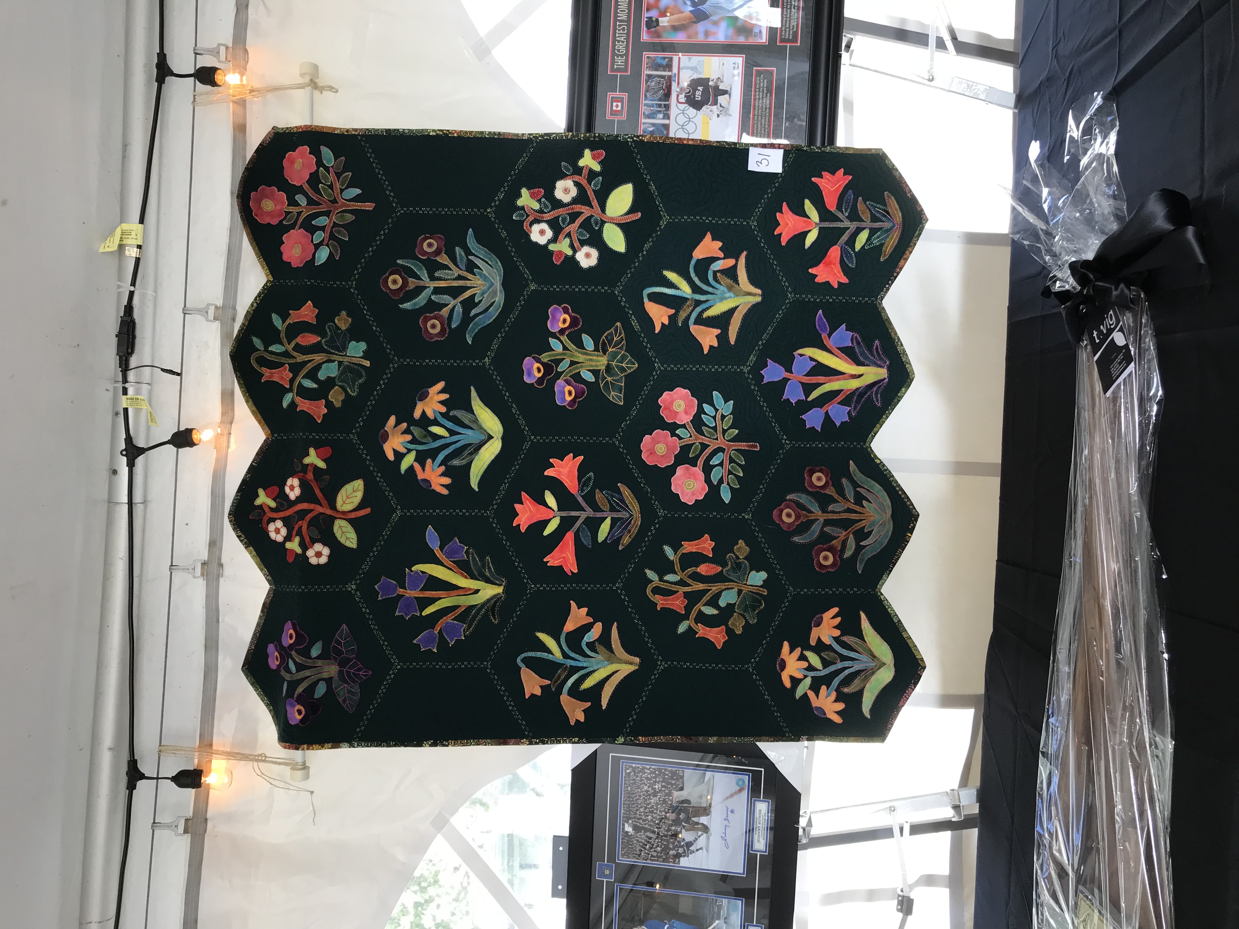 Courtepointe exposée dans un encan avec 18 alvéoles comprenant chacun des bouquets de fleurs colorés brodés.