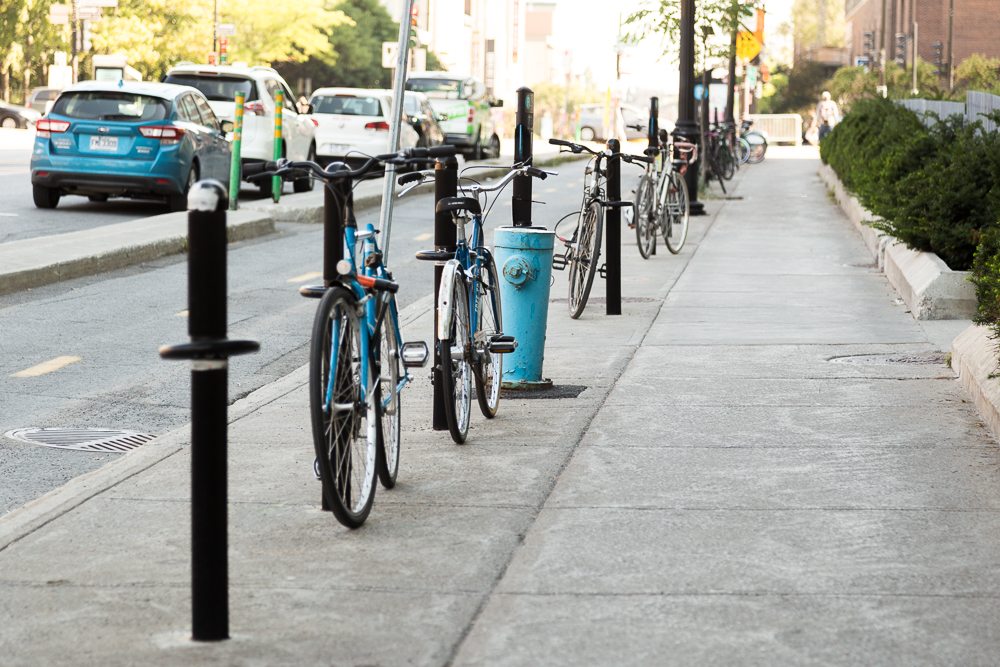 Vélos bien cordés à l'extérieur de la voie piétonne où il y a des poteaux.