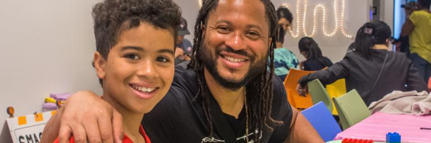 Un père et son fils sourient en construisant des blocs LEGO.