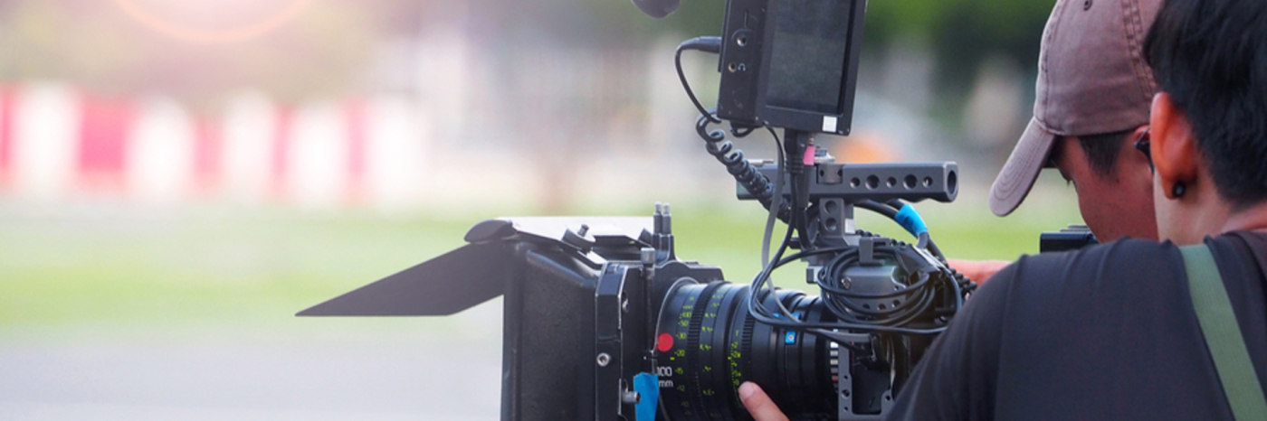 Un directeur photo tient une grosse caméra et filme. 