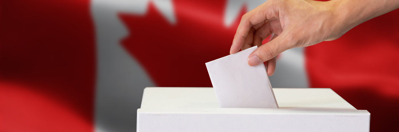 Une personne déposant son bulletin de vote dans une urne. Un drapeau canadien en arrière-plan.