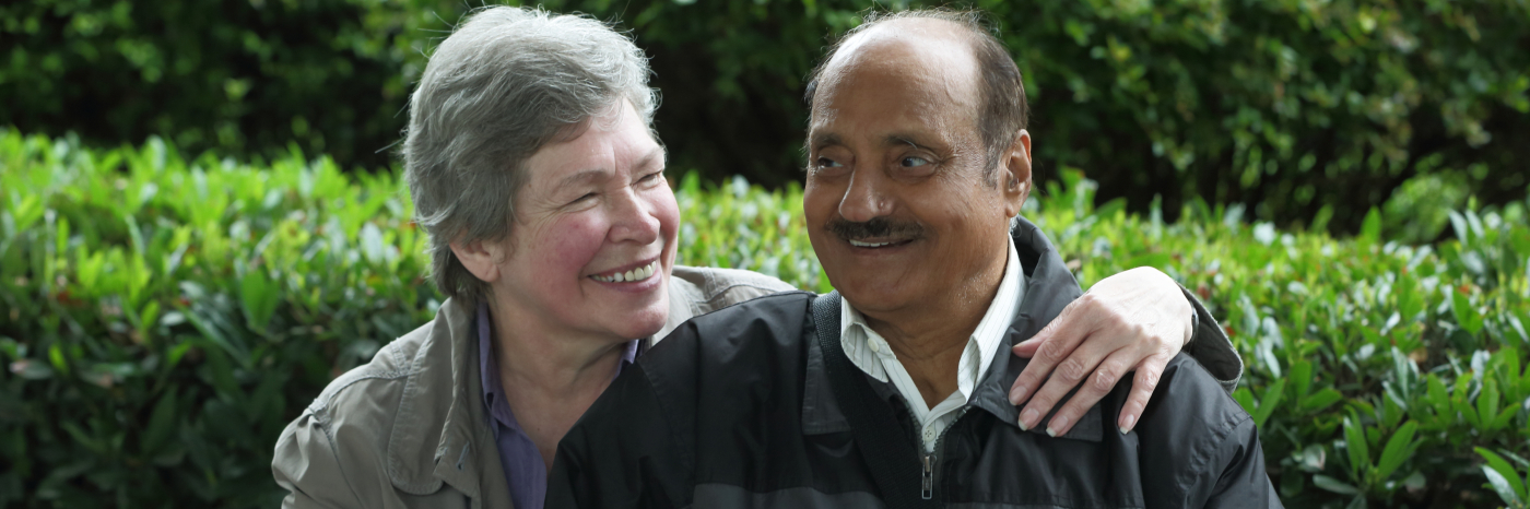 Un homme aveugle et une femme souriante assis sur un banc.
