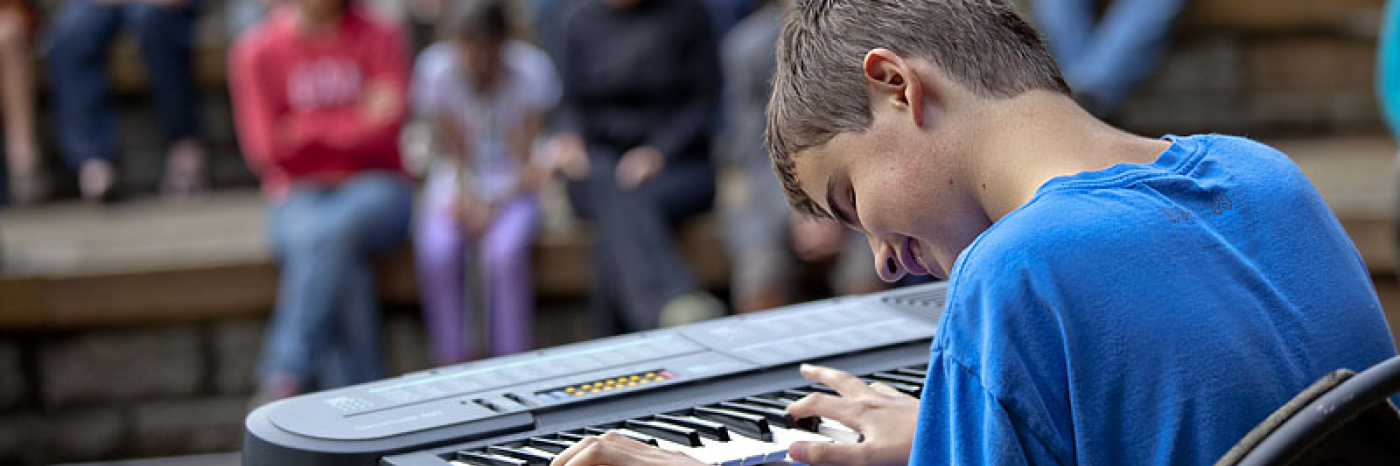 garçon ayant une perte de vision qui joue du clavier devant la foule 