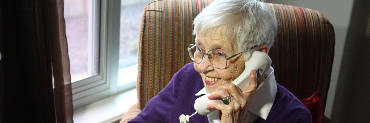 Une personne âgée parle au téléphone, tout sourire.