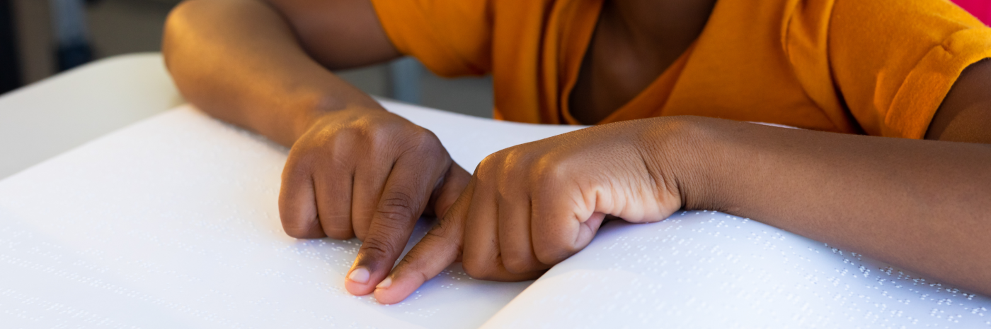 Un jeune enfant lit un livre en braille.
