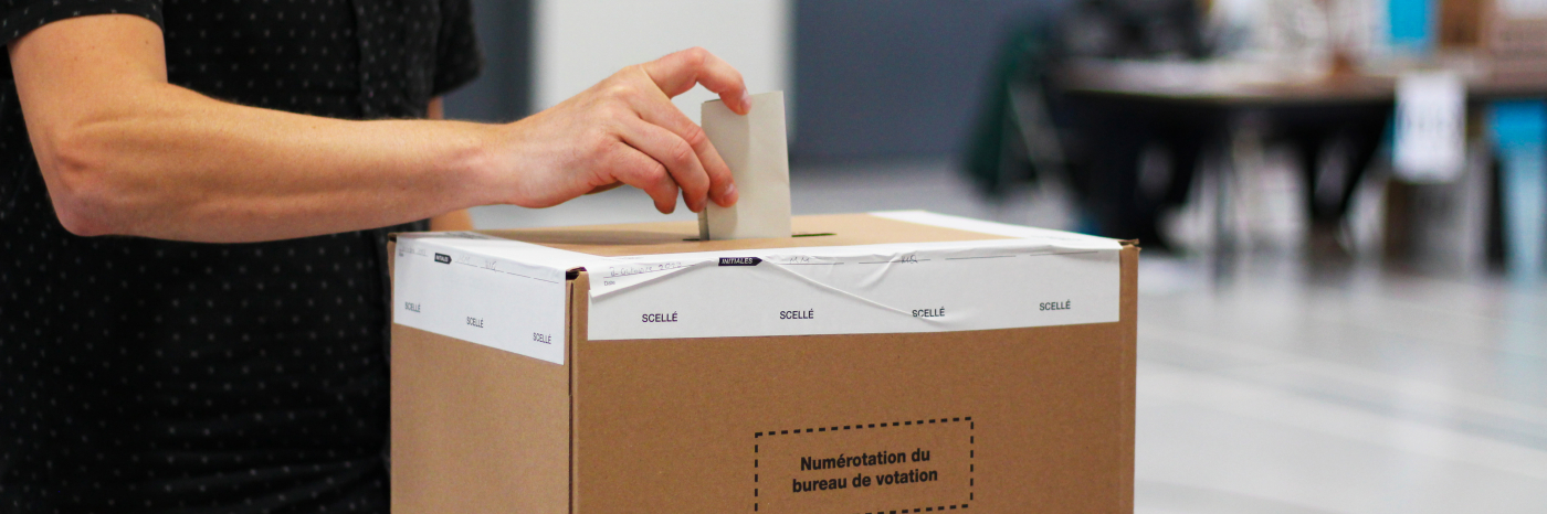 Un homme dépose son bulletin de vote dans une boîte d'Élections Québec