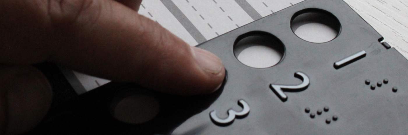 Gros plan sur une main qui explore au toucher un gabarit de vote tactile en relief, avec des chiffres 1, 2, 3 et leurs équivalents en braille, posé sur un bulletin de vote.