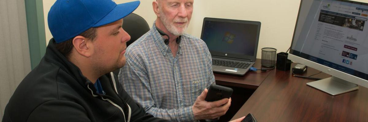 Two men smile and hold iPhones.